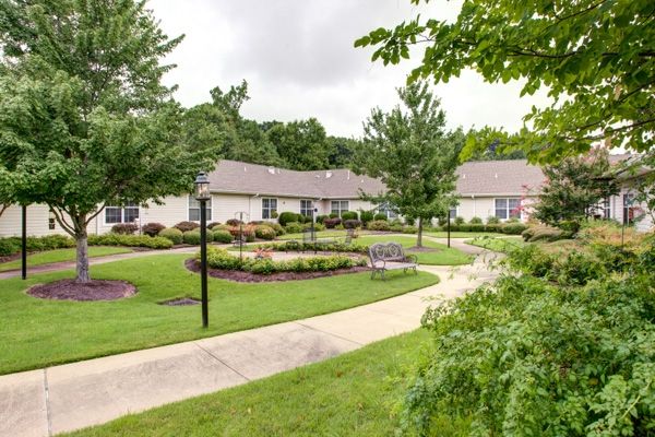 A scenic view of a well-maintained garden with a winding pathway, surrounded by houses and lush greenery.