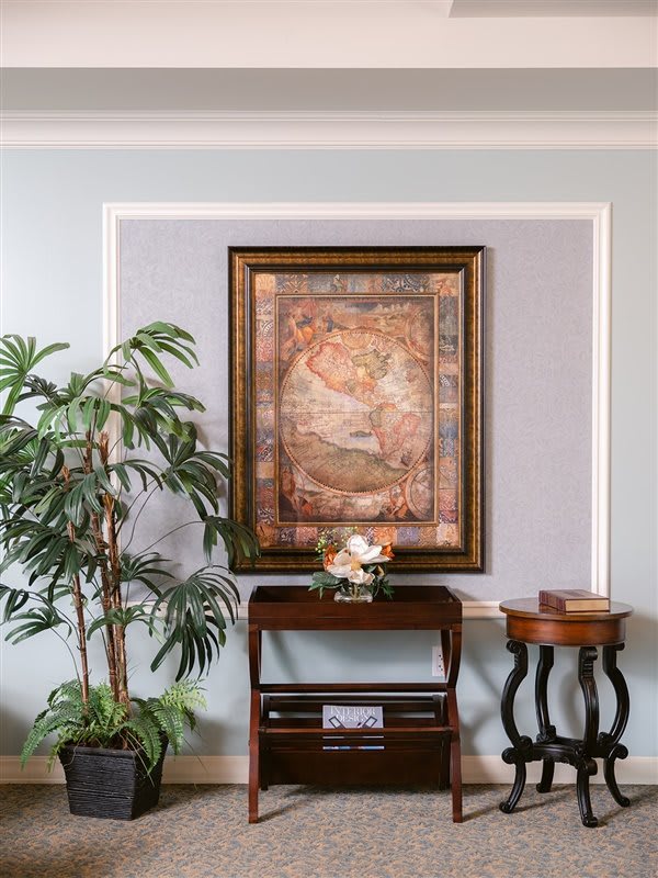A beautifully decorated room with a framed painting, indoor plant, and elegant furniture.