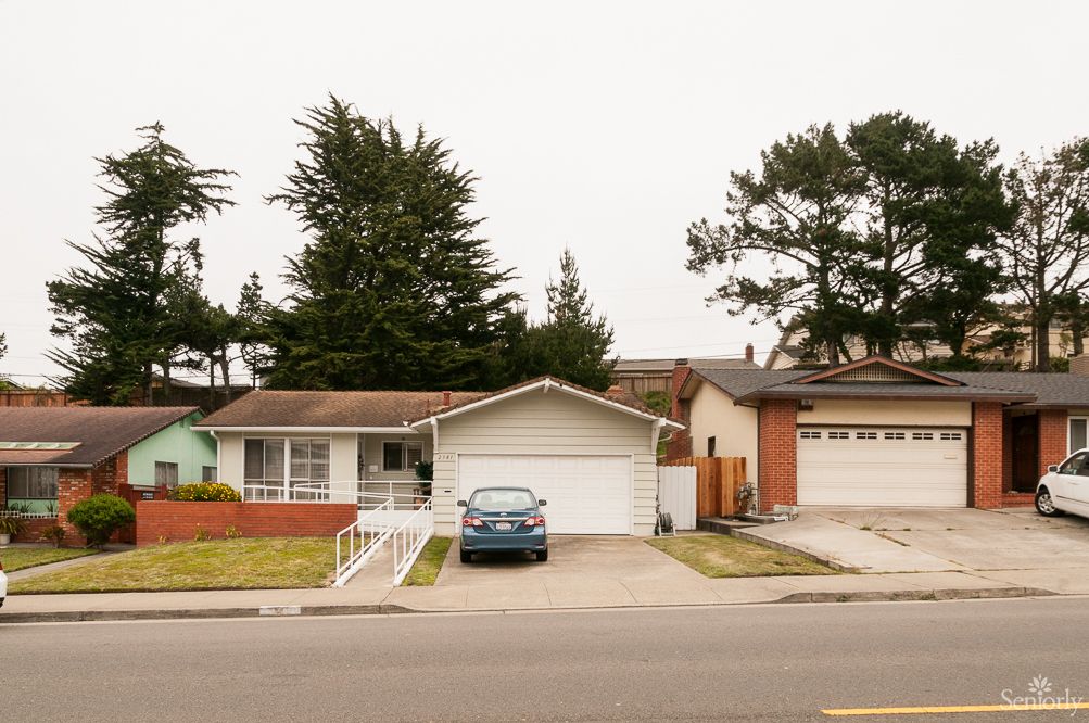 A suburban house with a driveway and a car parked in front.