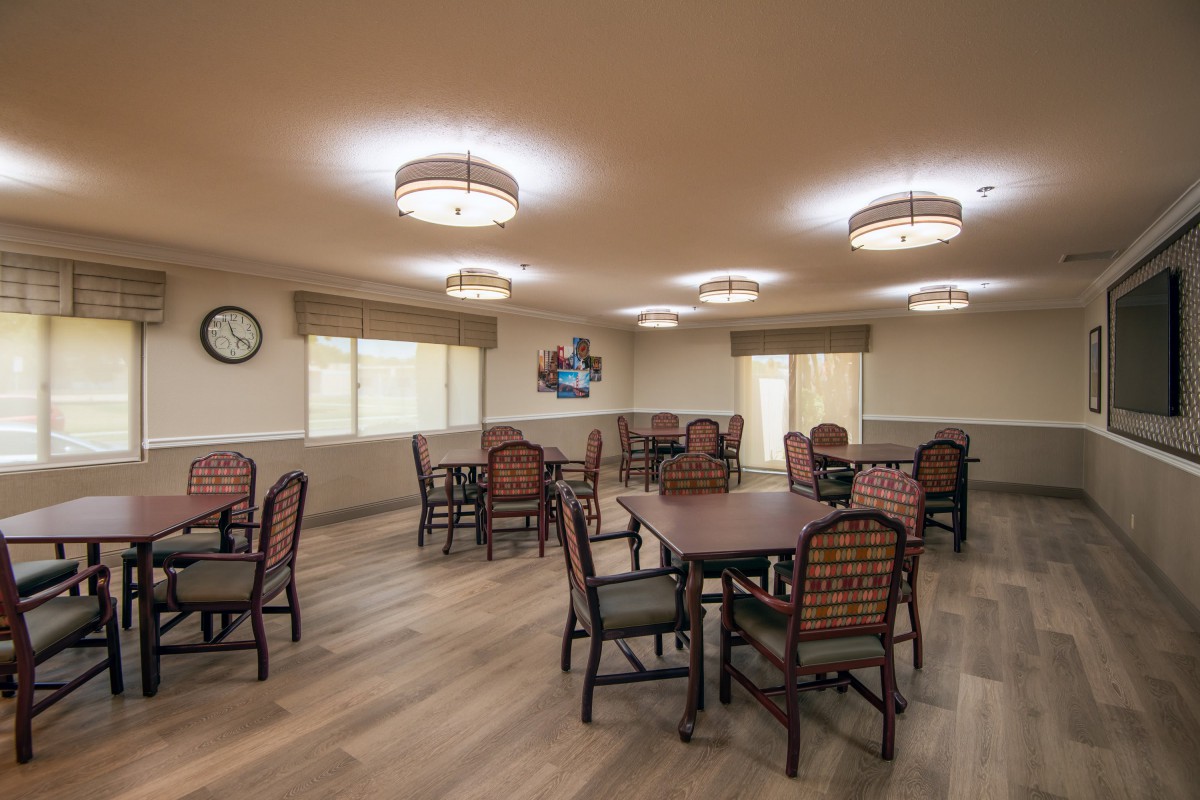 A spacious dining area with neatly arranged tables and chairs under warm, bright lighting.