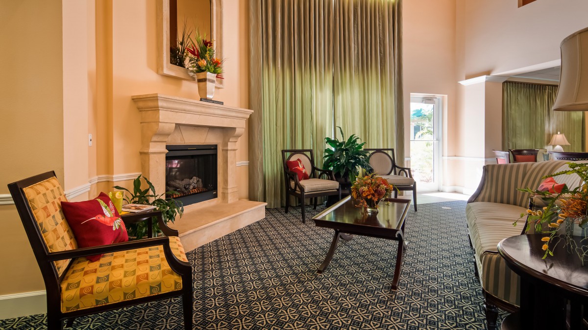 A cozy living room with elegant furniture, a fireplace, and green curtains.
