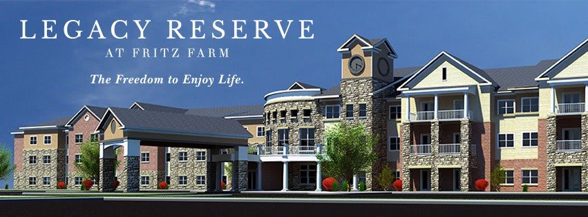 A luxurious residential building with a stone facade and clock tower, surrounded by trees.