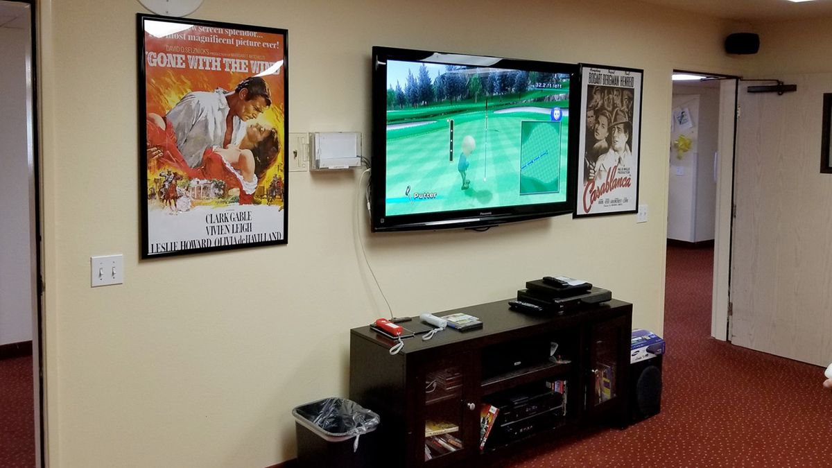 A cozy living room setup with a TV, gaming console, and movie posters on the wall.