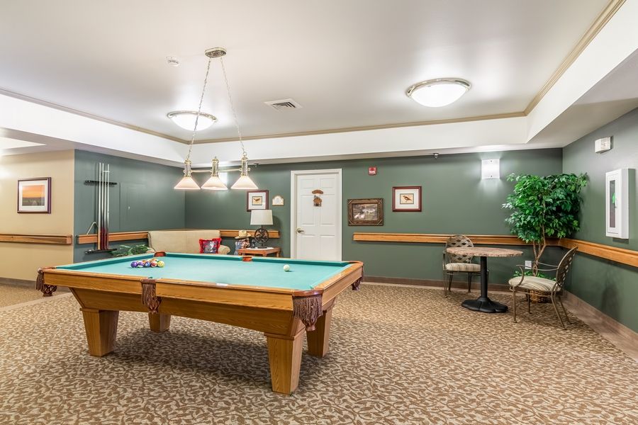 A recreation room featuring a pool table, seating area, and stylish lighting.