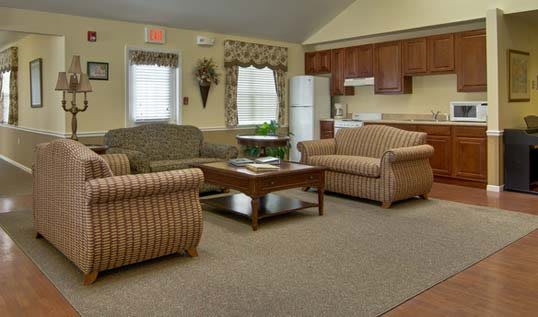 A cozy living room with comfortable seating and a kitchen area in the background.