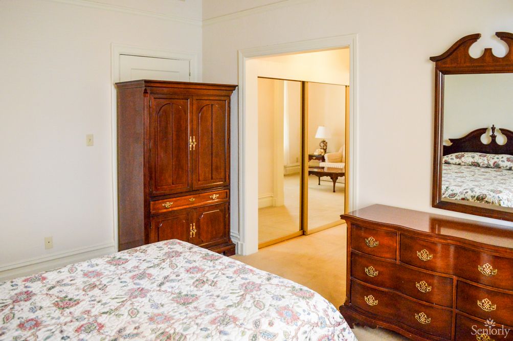 A cozy bedroom with wooden furniture including a wardrobe and dresser, featuring floral bedding.