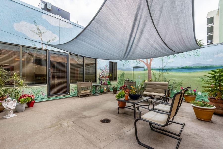 A cozy patio area with shaded seating and a mural on the wall.