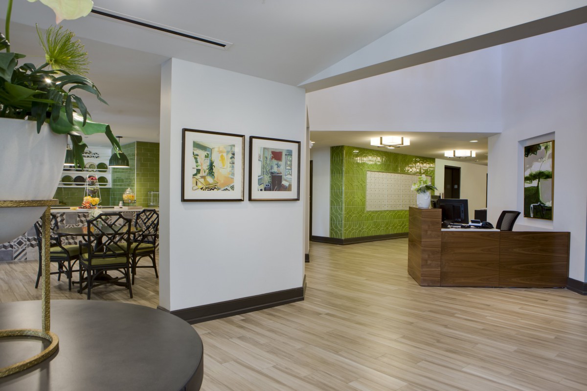 A modern lobby area with green accents, featuring a reception desk and artwork on the walls.