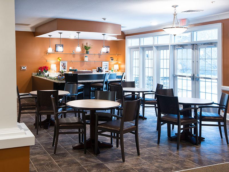 A cozy dining area with multiple tables and chairs, featuring warm lighting and a welcoming atmosphere.