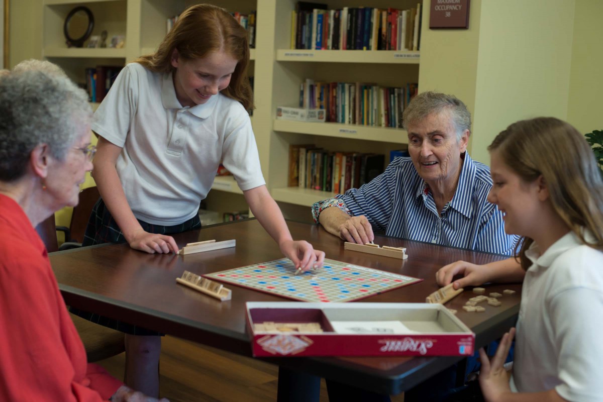 A group of people playing a board game together in a library setting.