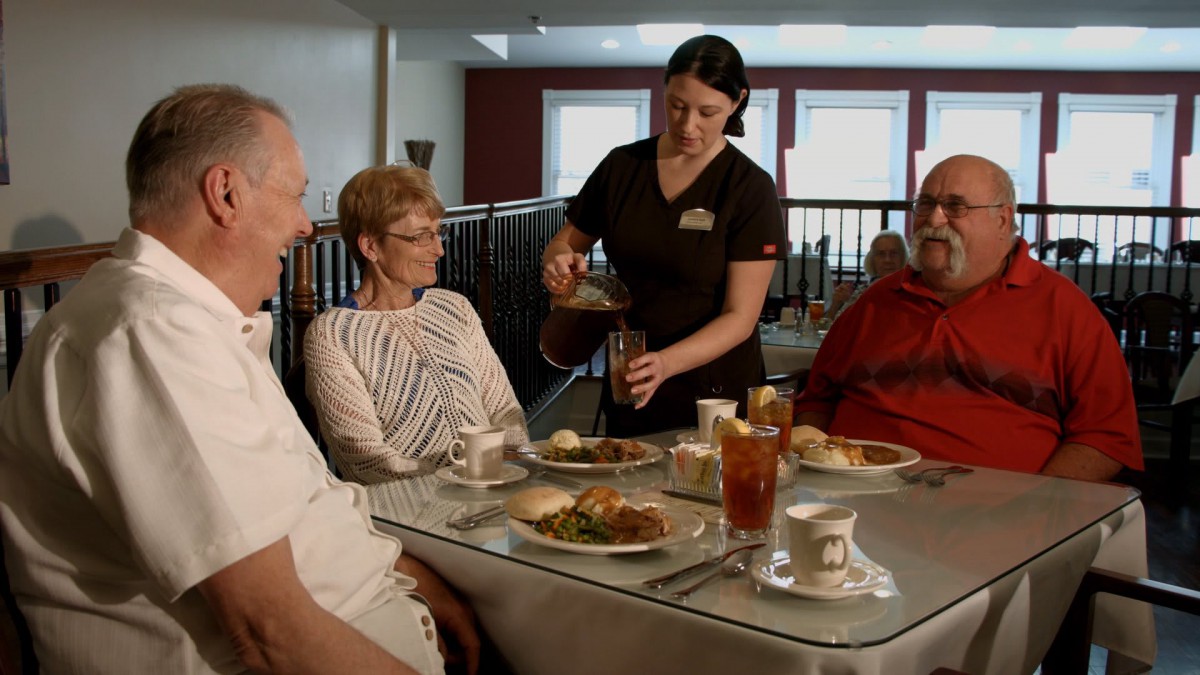 A waitress serves food to a group of people dining at a restaurant.