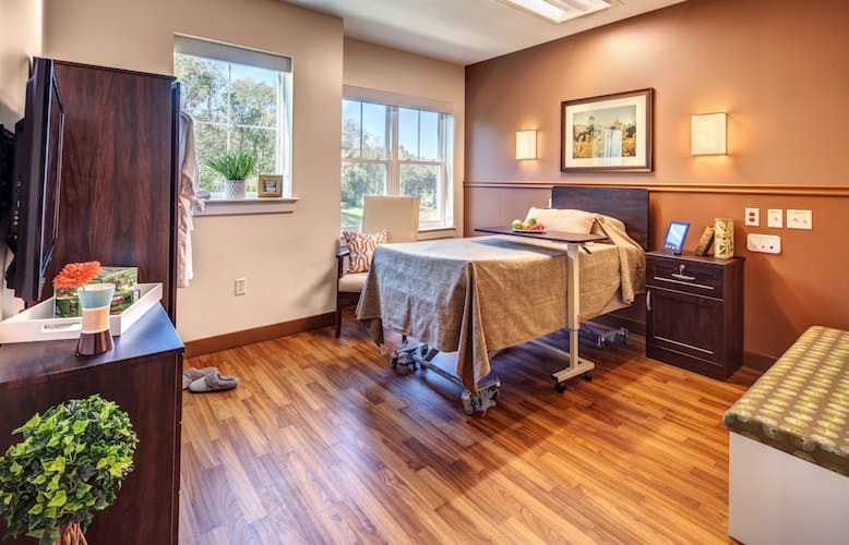 A well-lit hospital room featuring a single bed and wooden flooring.