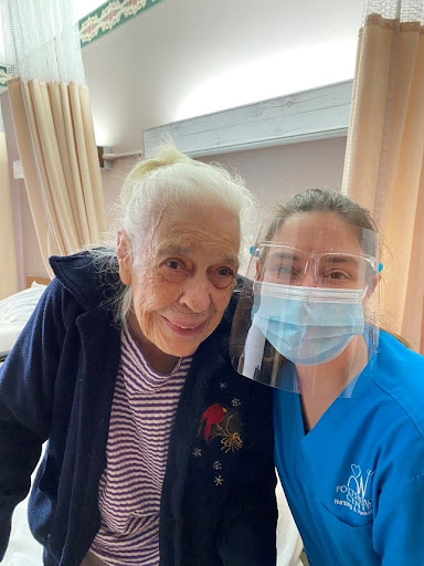 A caregiver and an elderly patient share a warm moment in a healthcare setting.