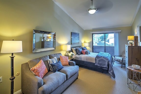 A cozy and stylishly decorated bedroom with a sofa, bed, and large window.