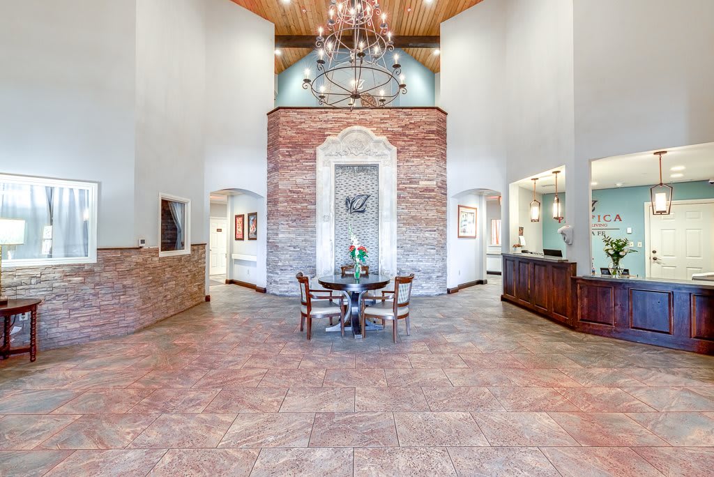A spacious lobby with a chandelier, brick accents, and welcoming reception area.