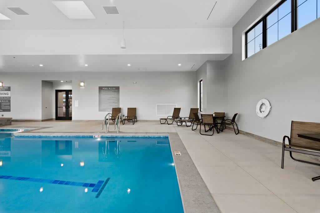 An indoor swimming pool area with seating and windows.