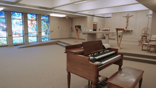A spacious interior of a music area featuring an organ, illuminated by natural light.