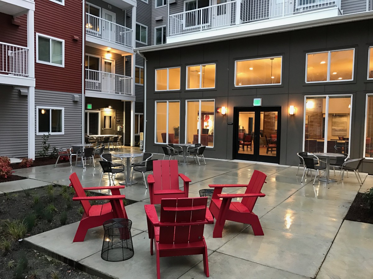 Outdoor patio area with red chairs in an apartment complex courtyard during the evening.