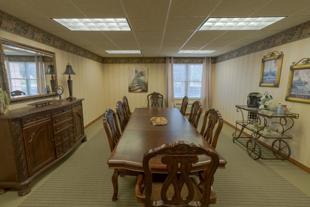 A well-lit conference room with a large wooden table and chairs, decorated with traditional furniture and art.