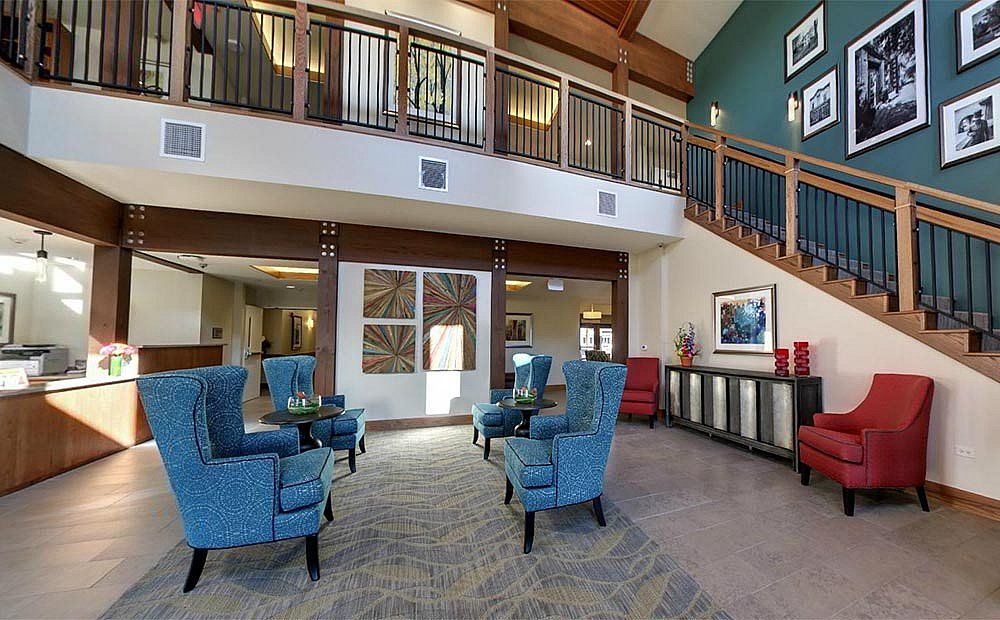 A modern lobby area featuring blue chairs and wooden accents, showcasing a spacious two-story design.