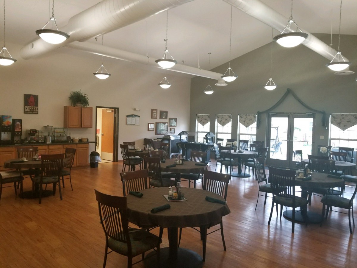 A spacious dining area with multiple tables and chairs, well-lit by overhead lights.