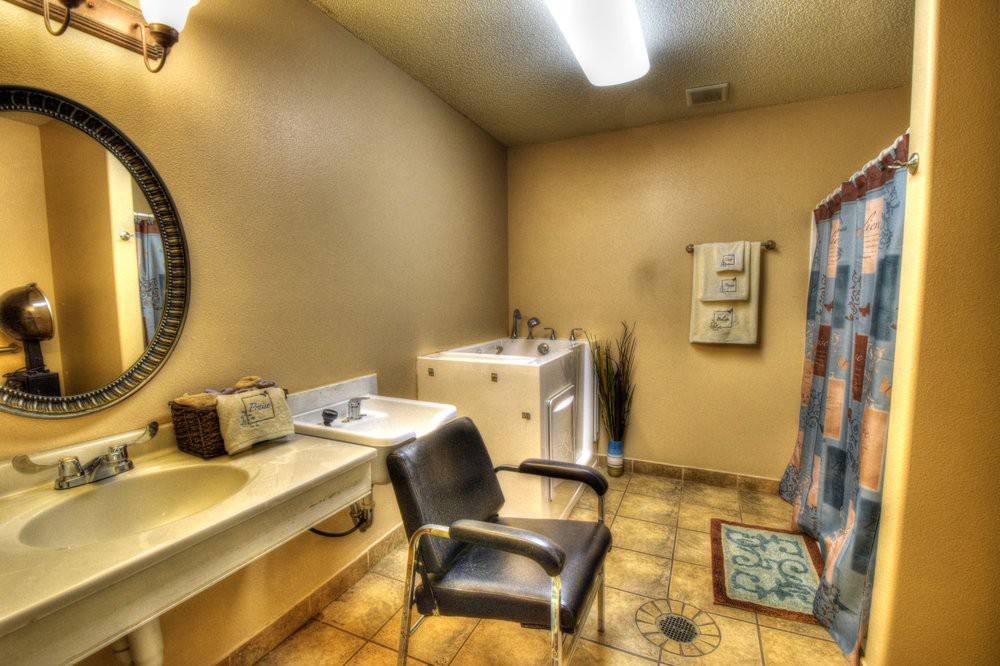 A clean bathroom with a sink, mirror, chair, and laundry appliances.