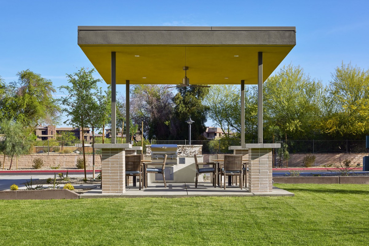 A modern outdoor gazebo with seating area and garden view.