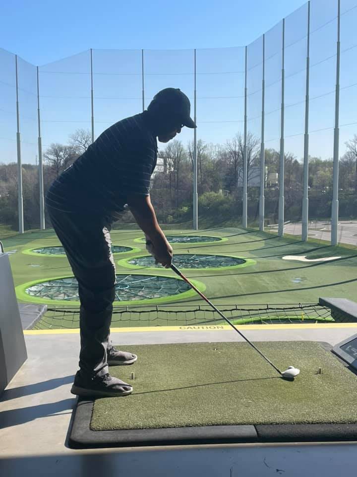 A person preparing to hit a golf ball at a driving range.