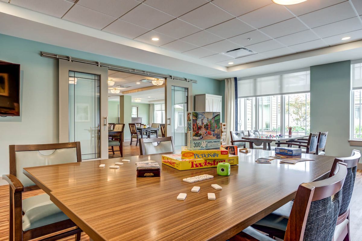 A modern meeting room with a large table, chairs, and board games on the table.