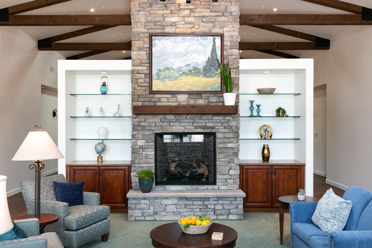A cozy living room featuring a stone fireplace, built-in shelves, and modern decor with comfortable seating.