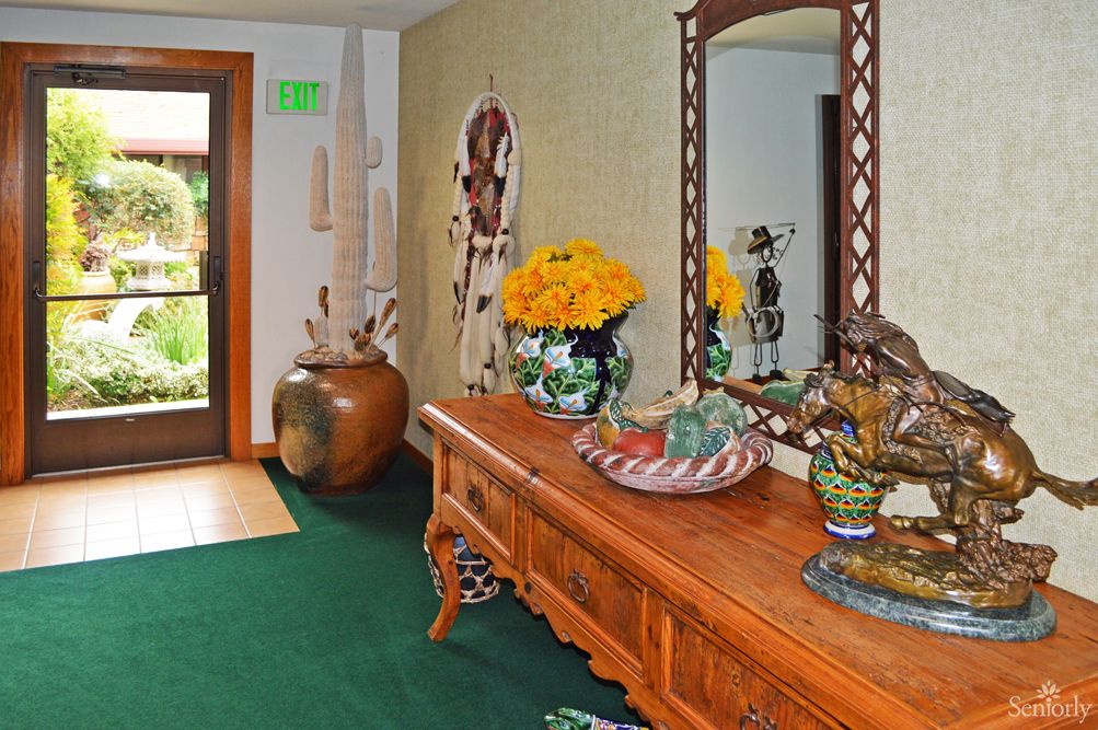 A warmly decorated entryway with a wooden table, mirror, and vibrant floral arrangement.