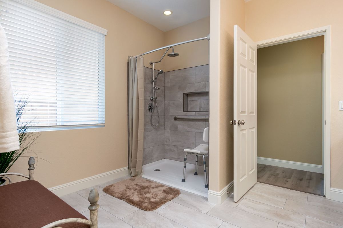 An accessible bathroom with a spacious walk-in shower, equipped with a curtain and a seating area.