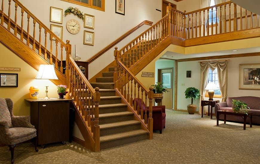 A cozy interior featuring a wooden staircase with carpeted steps, surrounded by warm lighting and decorative furnishings.