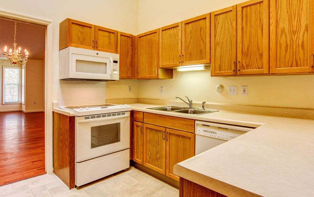 A kitchen with wooden cabinets, a microwave, stove, and sink.