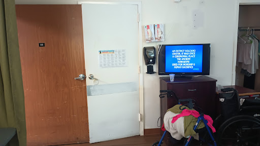 A view of a room featuring a door and a television with various items on the furniture.