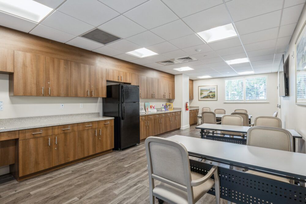 A modern office break room with wooden cabinets, a refrigerator, and seating area.