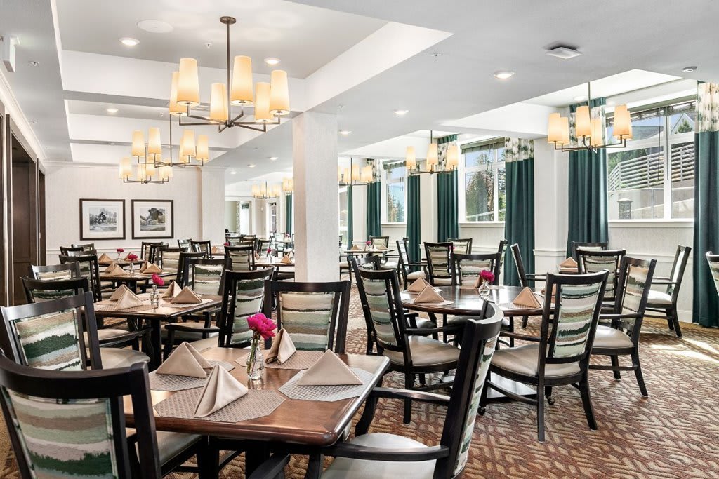 Elegant dining room with neatly arranged tables and chandeliers.