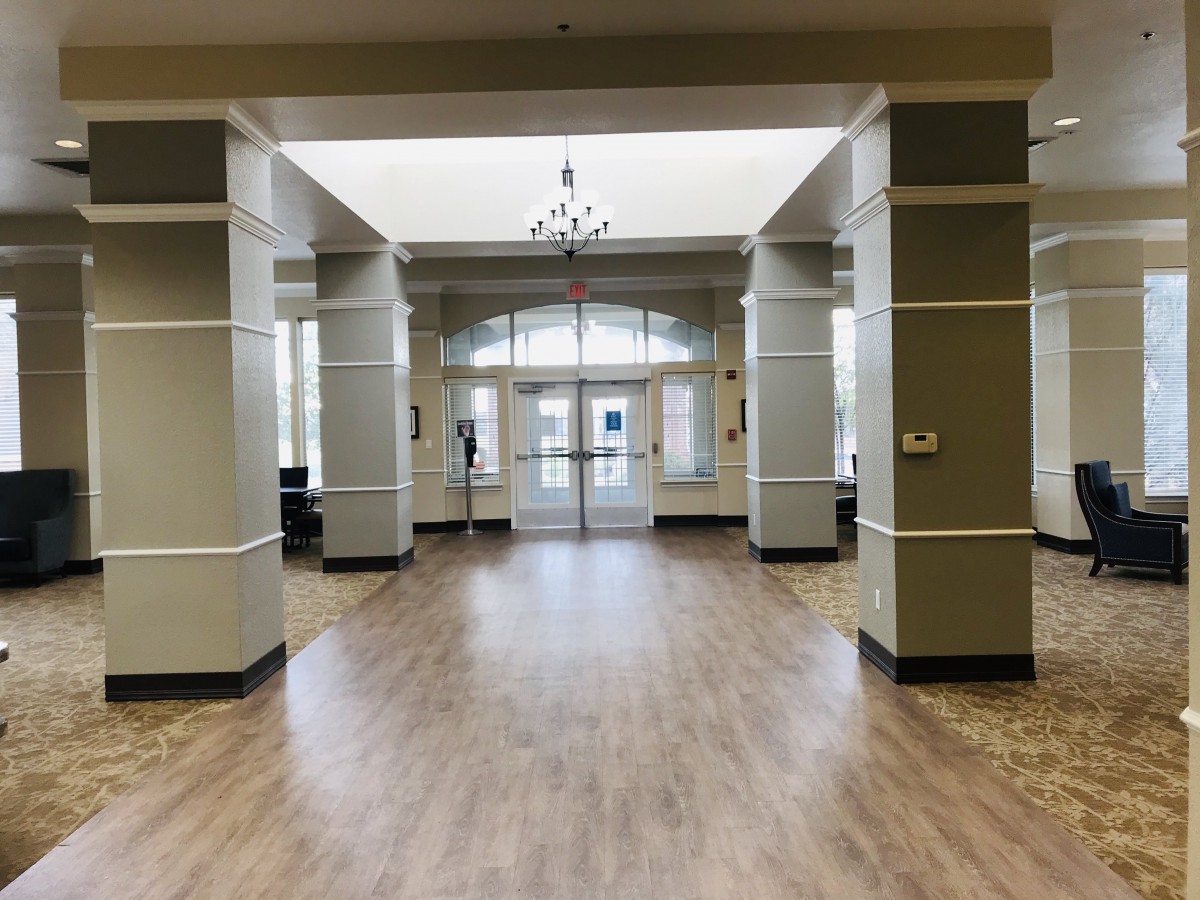 Spacious lobby with wooden flooring and large windows.