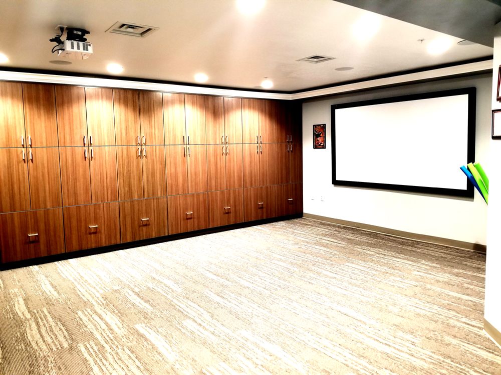 An empty meeting room with wood paneling and a large screen.