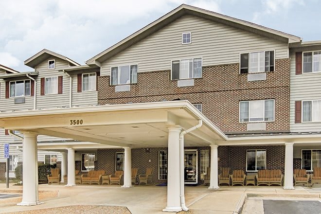 A multi-story residential building with a covered entrance and seating area.