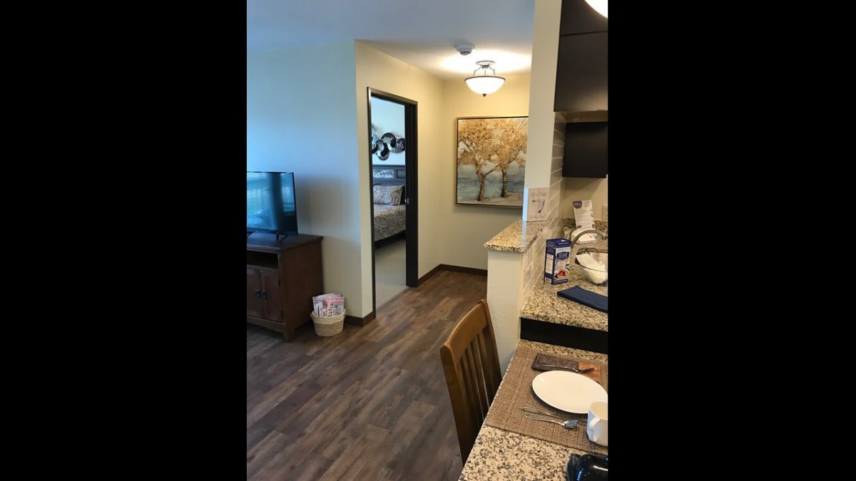 A cozy apartment interior featuring a living room with a TV and a kitchen area.
