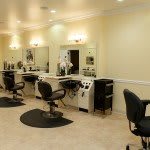 A well-lit hair salon interior with multiple styling stations and chairs.