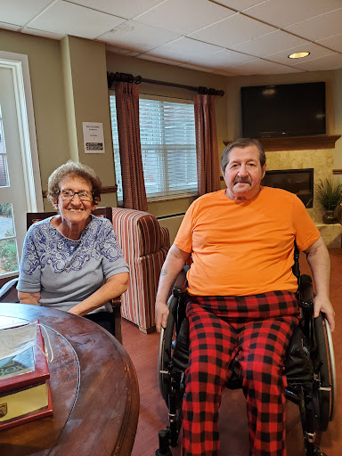 A cheerful moment shared between two seniors in a cozy indoor setting.