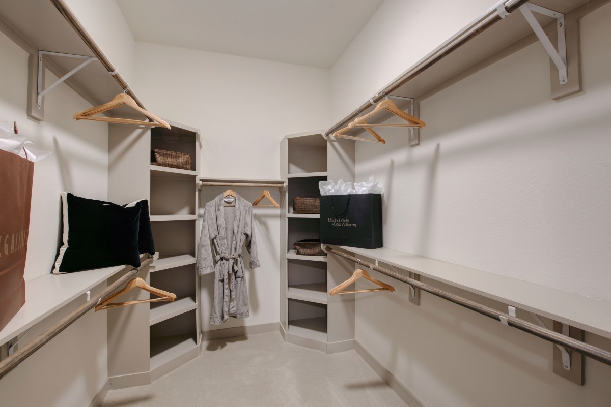 A spacious walk-in closet with organized shelves, hangers, and robes.
