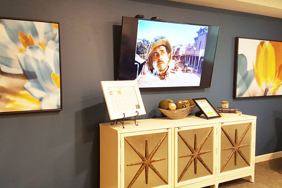 A well-decorated room featuring abstract art, a television displaying an image, and stylish furniture.