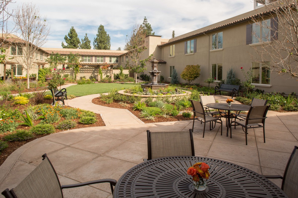 A beautifully landscaped courtyard with outdoor seating and a winding pathway surrounded by greenery.