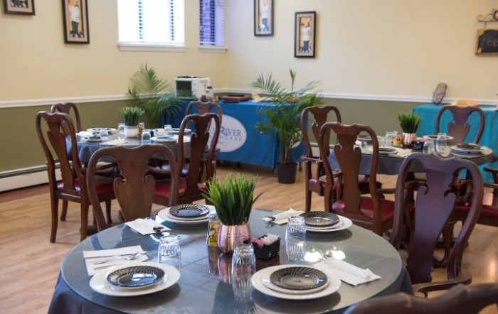 A cozy dining area with elegantly set tables and wooden chairs, exuding a welcoming atmosphere.