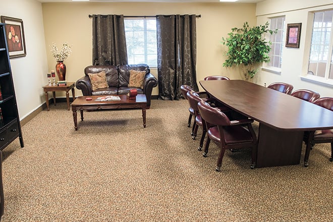 A cozy conference room with a meeting table, chairs, sofa, and decorative plants.