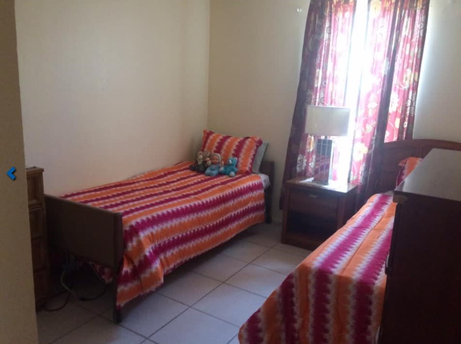 A cozy bedroom with two beds featuring bright, striped bedding.