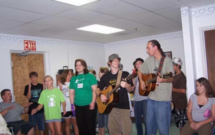 A group of people singing and playing guitars indoors.